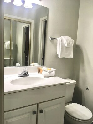 A bathroom with a white sink, mirror, and toilet. There is a towel rack with a towel and toiletries on the sink. - BEACHFRONT 5 STEPS TO BEACH ACCESS, BEACH SERVICE MARCH-OCT,  MANY NEW UPGRADES! (Destin)