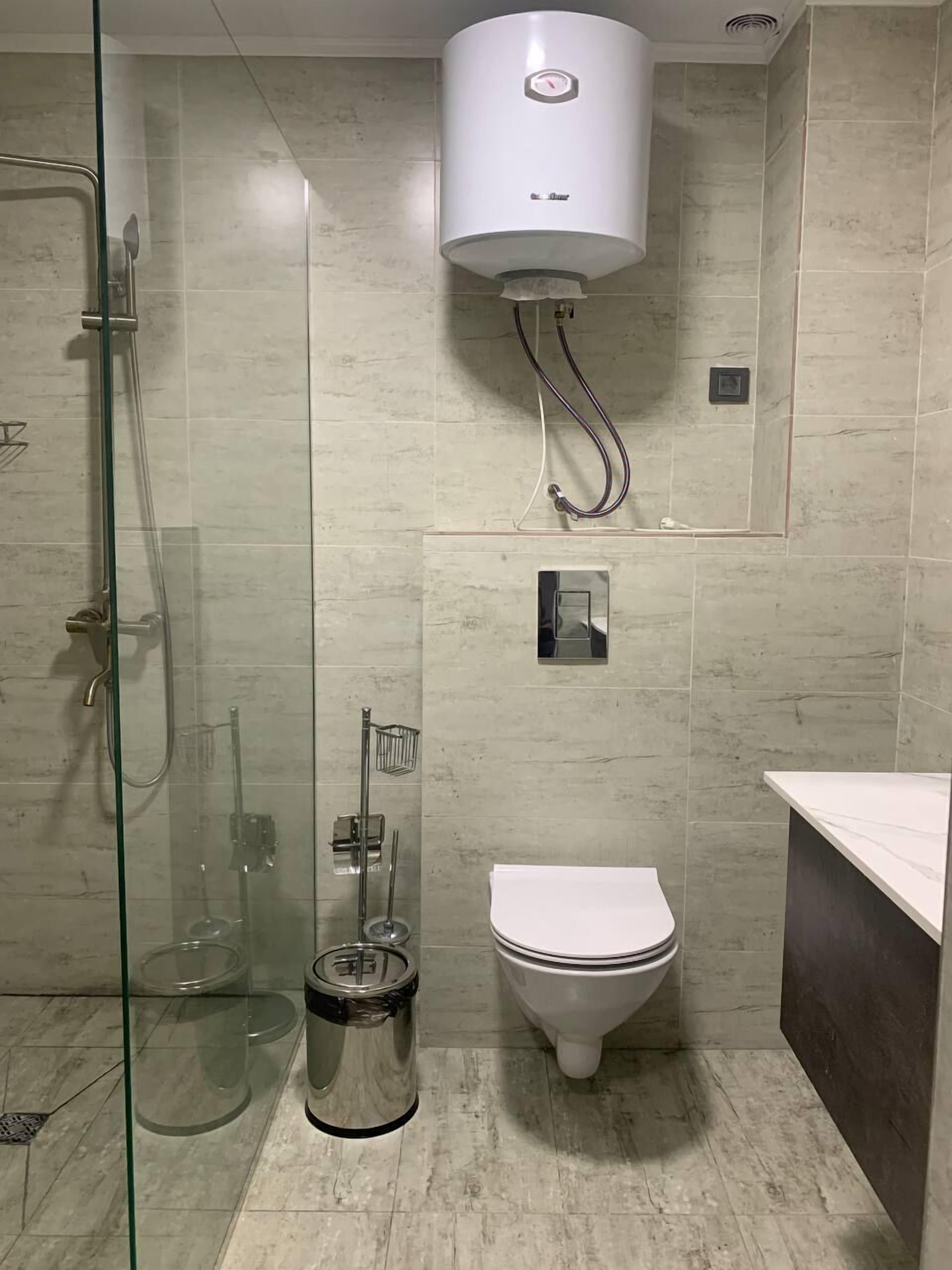 Uma casa de banho moderna com chuveiro separado por vidro, sanita e lavatório.