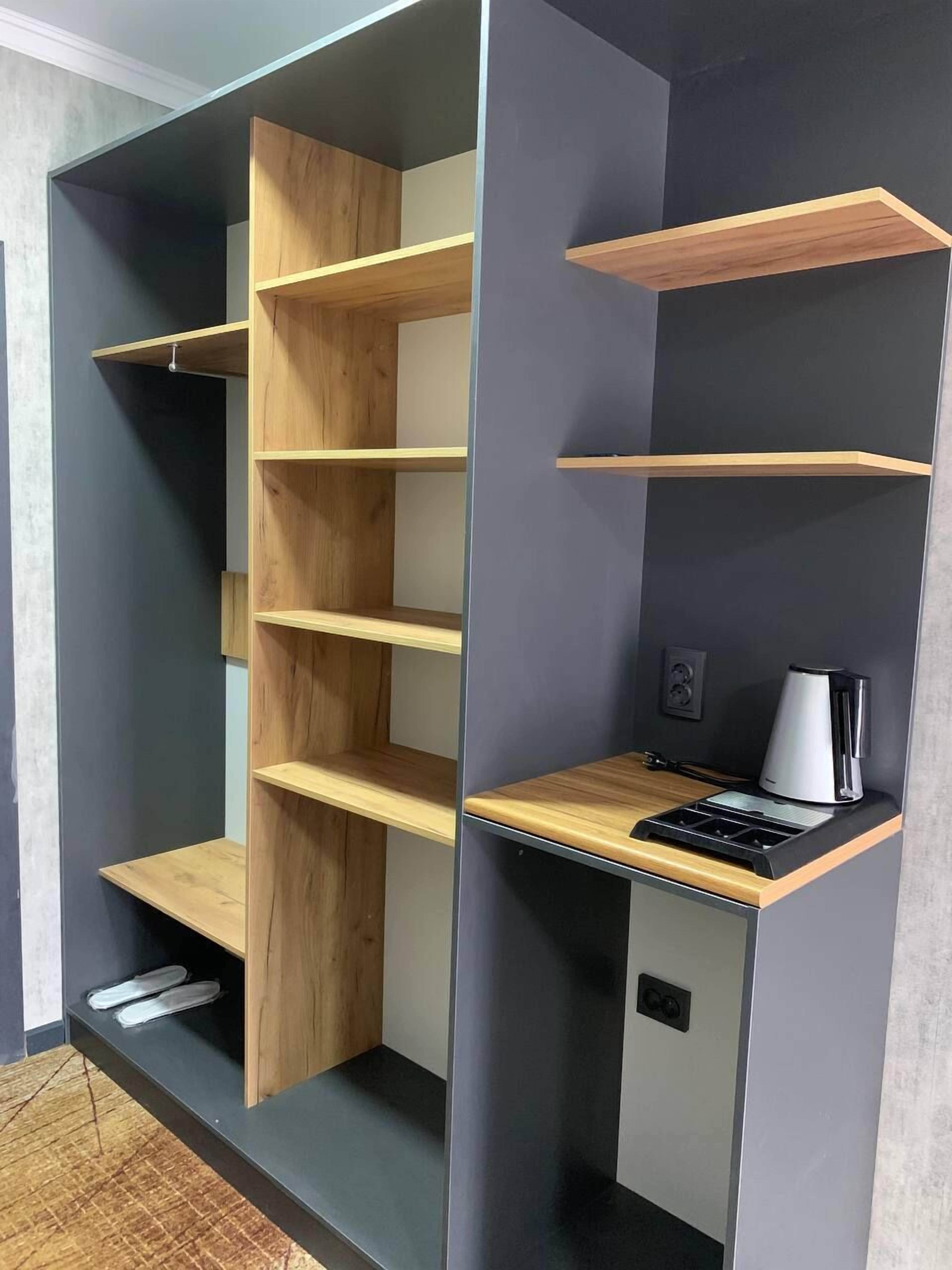 Una habitación moderna con estantes de madera integrados y un escritorio empotrado con cafetera.