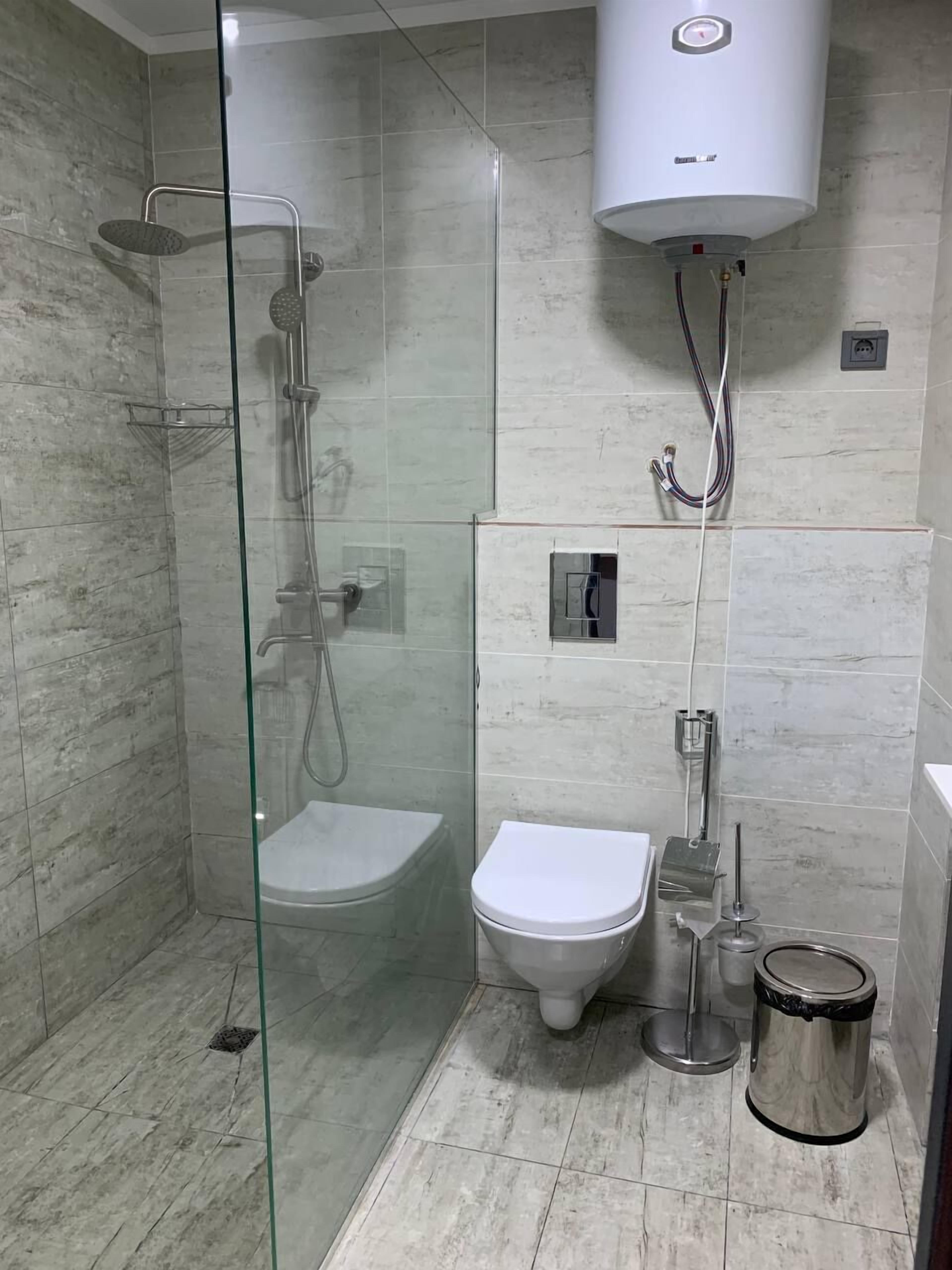 Un baño moderno con ducha de vidrio, inodoro y cubo de basura.