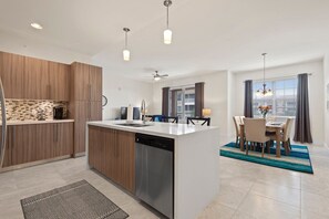 Une cuisine moderne avec des meubles en bois, un lave-vaisselle et un coin repas comprenant une table et des chaises.