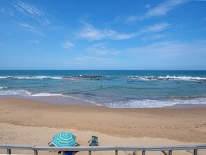A beach with a clear sky, calm sea, and a sandy shore.