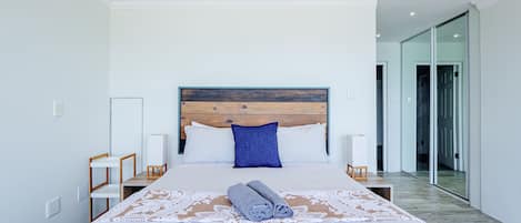A modern bedroom with a large bed, a wooden headboard, and a hanging light fixture.