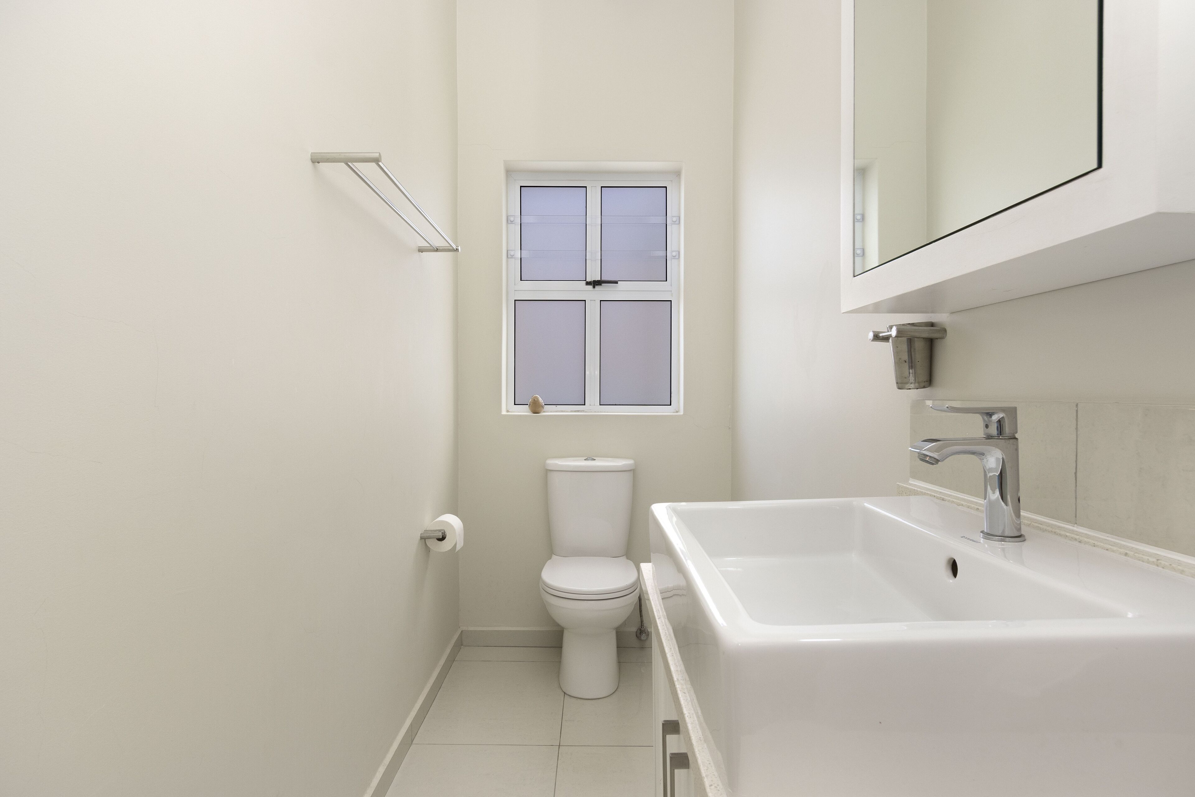 A small, clean bathroom with a toilet, a window, and a sink.
