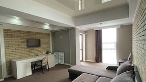 Ein geräumiges Zimmer mit einem großen Bett, einem Schreibtisch und einem Stuhl.