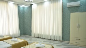 A hotel room with two beds, a wardrobe, and an air conditioning unit. - Foothills villa (Gabala)