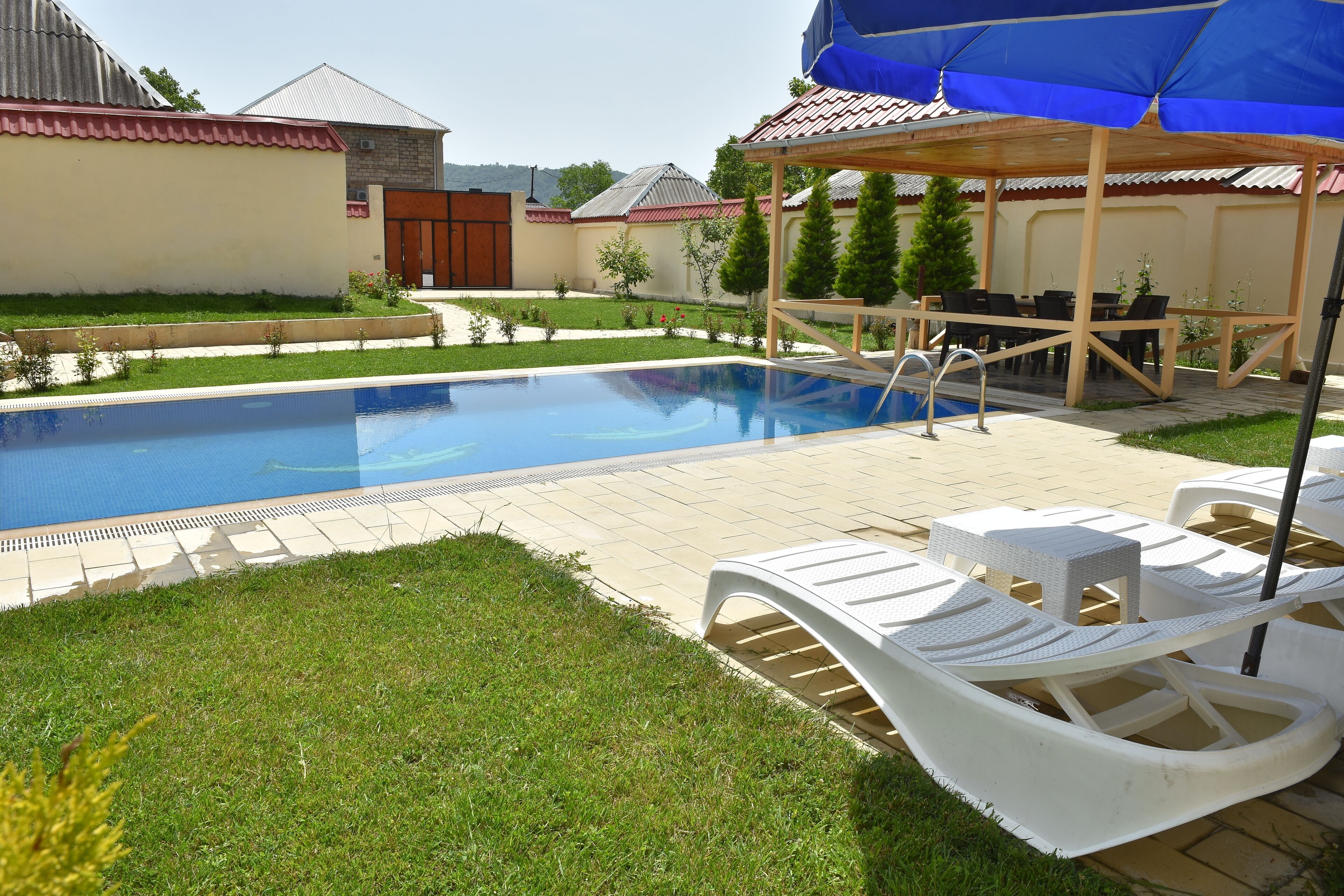A swimming pool with lounge chairs and a covered seating area.
