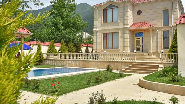 A two-story building with a swimming pool, surrounded by greenery and a mountainous backdrop. - Foothills villa (Gabala)