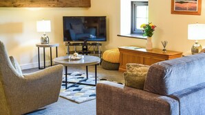 A living room with a television, two lamps, a round coffee table, and a sofa. - The Studio at Malt Kiln Cottage (Grizebeck, near Kirkby-in-Furness)