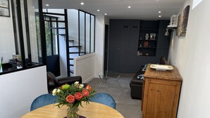 Un espace repas moderne avec une table ronde en bois, des chaises bleues et un vase de fleurs.