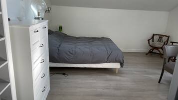 Una camera da letto con un letto, una cassettiera, una sedia e una lampada.