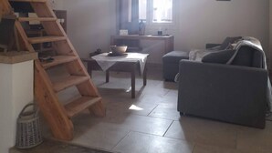 A living room with a wooden staircase, a table with a basket, a sofa, and a window with curtains.