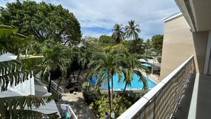 A view of a pool area surrounded by palm trees and greenery, with a clear sky above. - Penthouse in Paradise! (Key West)