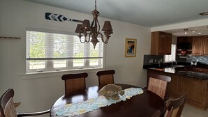 A dining area with a round table, chairs, a chandelier, and a kitchen in the background. - Penthouse in Paradise! (Key West)