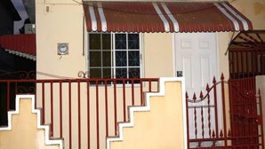 Un bâtiment avec une porte blanche, une fenêtre à carreaux et un portail métallique rouge.