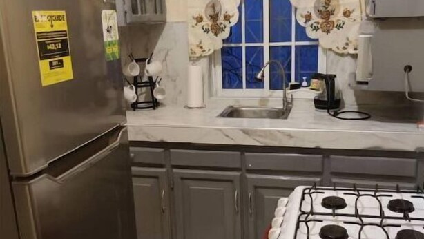 Une cuisine de taille réduite équipée d’un réfrigérateur, d’une cuisinière, d’un évier et de placards.