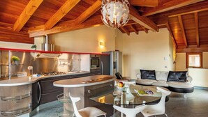 A modern kitchen with a central island, a dining area with a glass table, and a living area with a sofa.