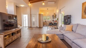 Un salon moderne avec une table basse en bois, un canapé gris et un téléviseur posé sur un meuble en bois.
