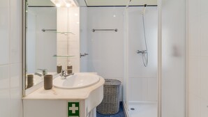 A modern bathroom with a sink, mirror, and shower.