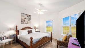 A bedroom with a wooden bed, a nightstand, a chair, a window with a view, and a ceiling fan. - Home on the Golf Range - Holiday Hills Branson - Golf Resort - Outdoor Pools (Branson)