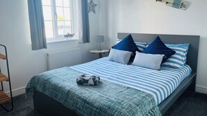 Un dormitorio con cama, adorno con forma de estrella, estante con un modelo de barco y una lámpara.