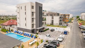 A modern hotel with a rooftop pool, multiple balconies, and a parking area. - Ria Apartments (Navodari)