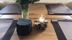 A dining table with a vase of yellow roses, a candle, and a decorative item on a placemat. - Cozy apartment 2 in the DG in the Sonnenhof (Dippoldiswalde)