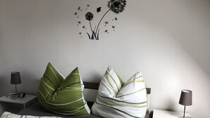 A bedroom with a bed, pillows, a nightstand, a lamp, and a wall decoration. - Cozy apartment 2 in the DG in the Sonnenhof (Dippoldiswalde)