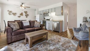 Ein modernes Wohnzimmer mit einem braunen Sofa, einem Holztisch und einem gemusterten Teppich.