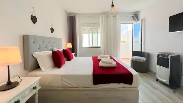 A hotel room with a bed, a desk, a lamp, a TV, and a window. - Isa SkyHouse Algarve (Portimão)