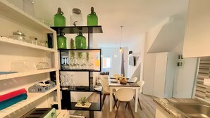 A modern kitchen with white cabinets, a black countertop, and a dining area with a table and chairs. - Isa SkyHouse Algarve (Portimão)