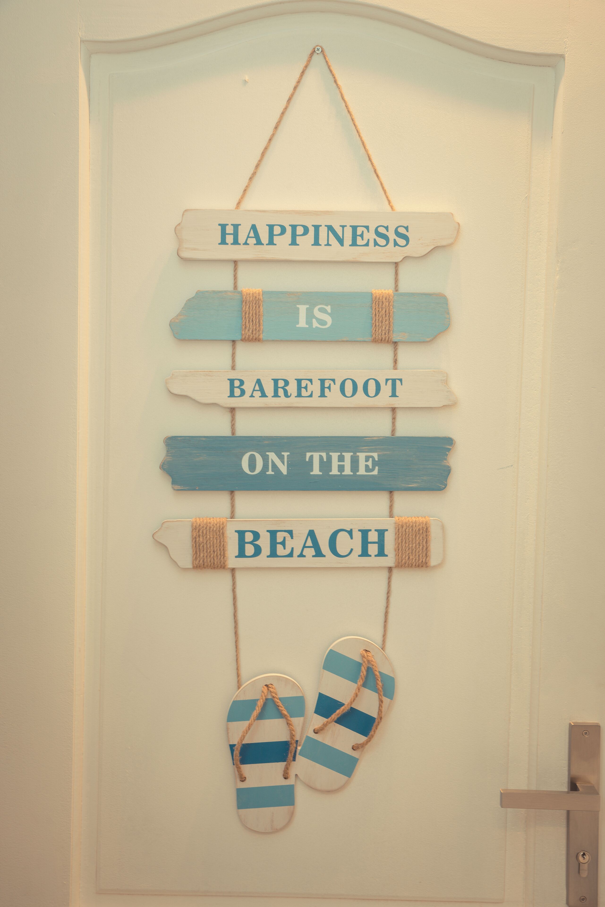 Un élément de décoration murale comprenant une citation inspirante et une paire de tongs.