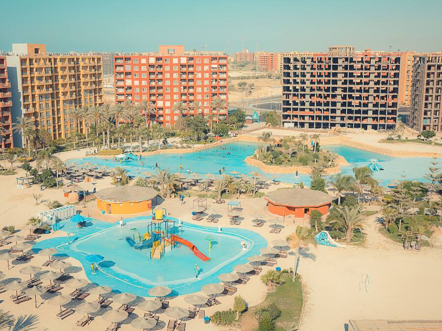 A resort with multiple swimming pools, sun loungers, and palm trees.