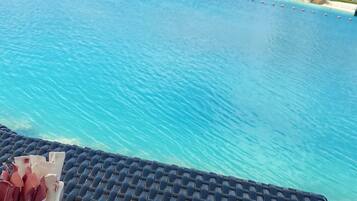 A view of a clear blue pool with a lounge area in the foreground.