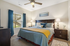 Restful retreat with a large bed, nightstands, and a ceiling fan.