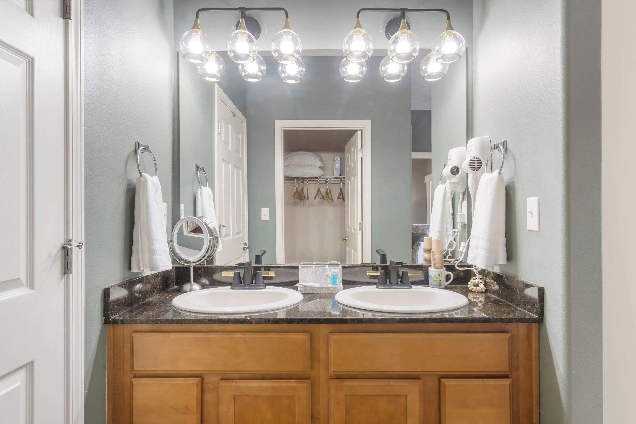 A bathroom with two sinks, a mirror, and a vanity with a countertop.