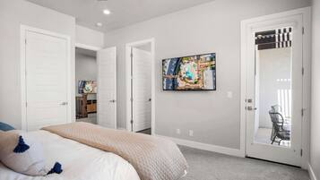 A bedroom with a bed, a large window, and a door leading to a balcony.