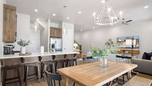 A modern kitchen with a wooden island, bar stools, and pendant lighting. - Coral Paradise Community Pool (Santa Clara)