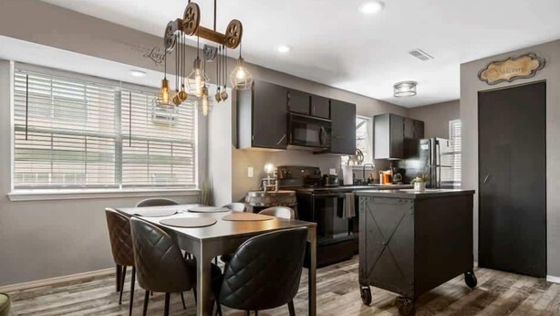 A modern kitchen with dark cabinetry, a central island, and pendant lighting.