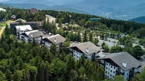Ein Resort mit mehreren Gebäuden, umgeben von dichtem Wald und Bergen im Hintergrund.