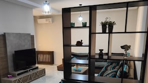 Un salon moderne avec un téléviseur, un canapé et une étagère décorative.