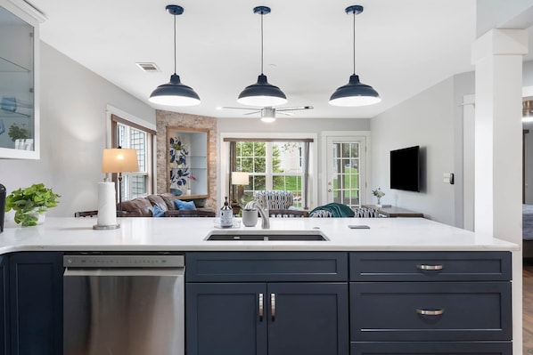A modern kitchen with a large island, dark cabinetry, and pendant lighting.