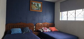 A room with two beds, a painting on the wall, and a window with a view.
