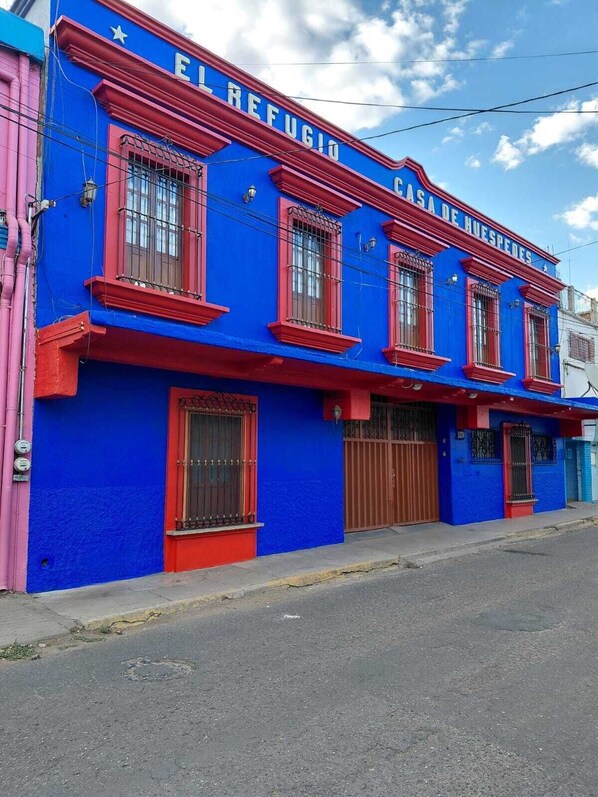 A building with a blue facade and red accents, featuring multiple windows and a gated entrance. - Casa Refugio Zocalo/8 bedrooms & 9 bathrooms (Oaxaca de Juárez)