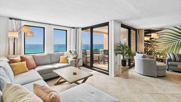 A modern living room with a large sofa, a coffee table, and a view of the ocean through large windows. - SnowBirdsWelcome-GulfView-HeatedPool (Destin)