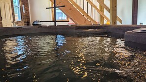 Un bain à remous avec un escalier en bois et un mur de briques en arrière-plan.