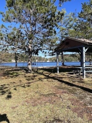 A covered picnic area with a bench and a swing, surrounded by trees and a body of water. - Rustic & Renovated Hot Tub/Game Room Sleeps 8ppl (Antrim)