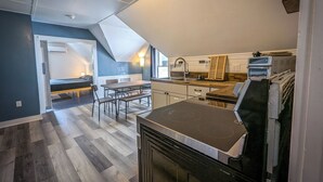 Une cuisine moderne dotée d’un four encastré, un coin repas avec un banc et une vue sur la chambre adjacente.