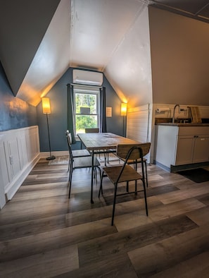 A dining area with a table and chairs, a window with a view of greenery, and a kitchenette with a refrigerator and sink. - Rustic & Renovated Hot Tub/Game Room Sleeps 8ppl (Antrim)