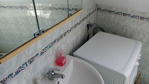 Ein Badezimmer mit einem weißen Waschbecken, einem Spiegel und einer Dusche.